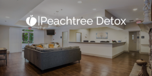 Bright clinic lobby with gray sectional sofa, wood floors, and staffed reception desk Peachtree Detox branding