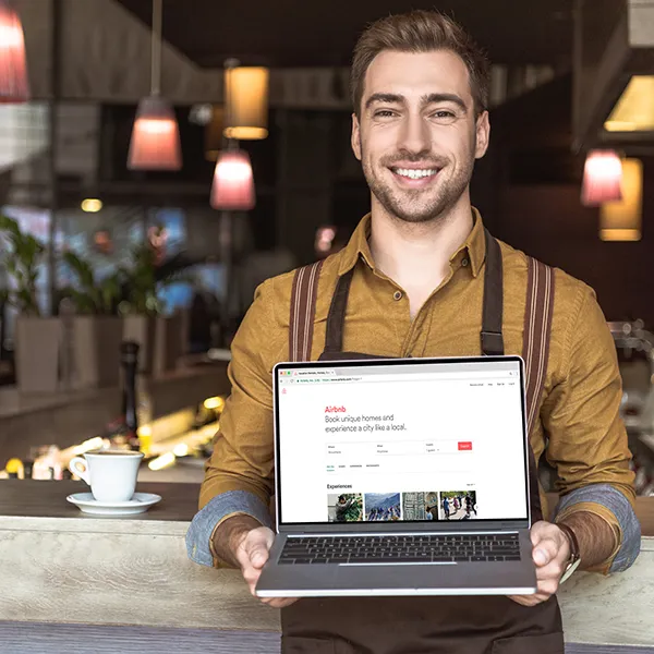 handsome young waiter holding laptop with his business on the map