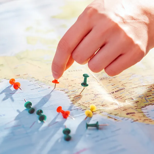 partial view of woman and colorful push pins on the map