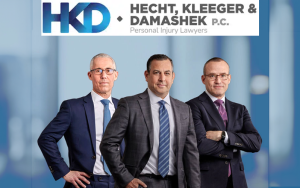 Three personal injury attorneys in suits pose before city backdrop, HKD Hecht Kleeger Damashek logo above