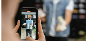 Team meeting in a modern office: a man presents while two women take notes on laptops at a long table